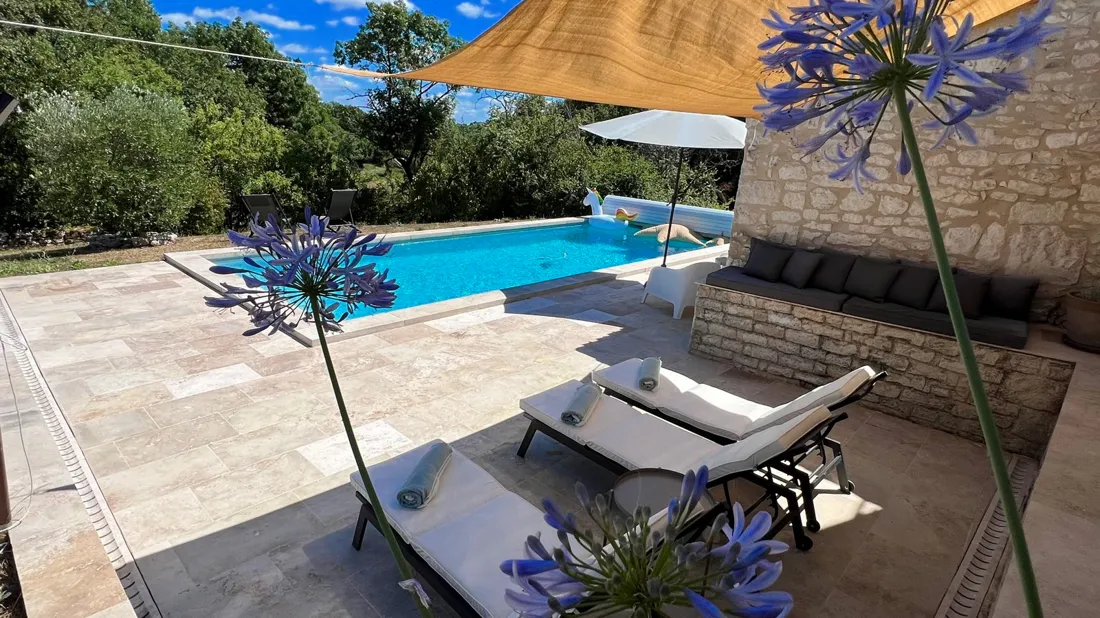 Transats au bord de la piscine, agapanthes en fleurs